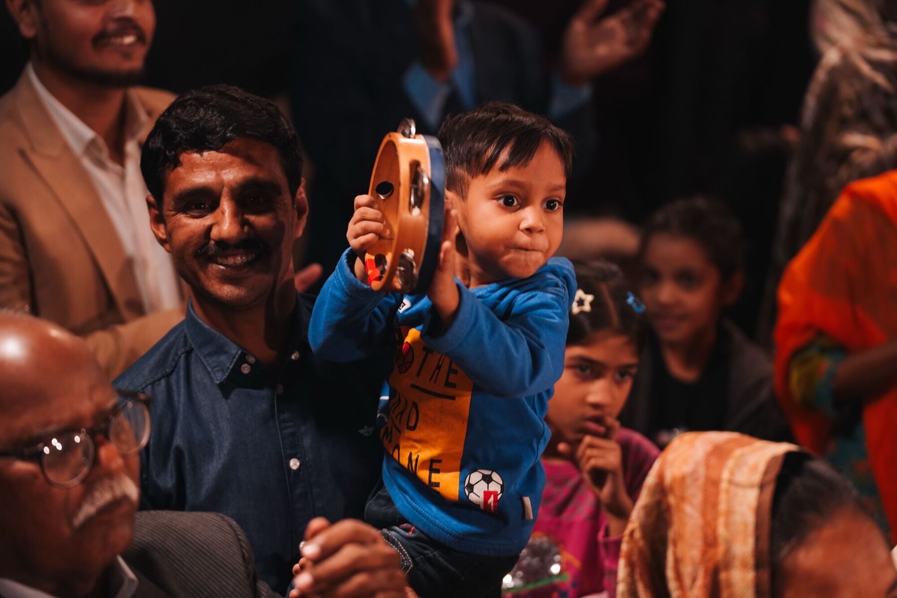 A father and his little boy with a tambourine, smiling at the crusade
