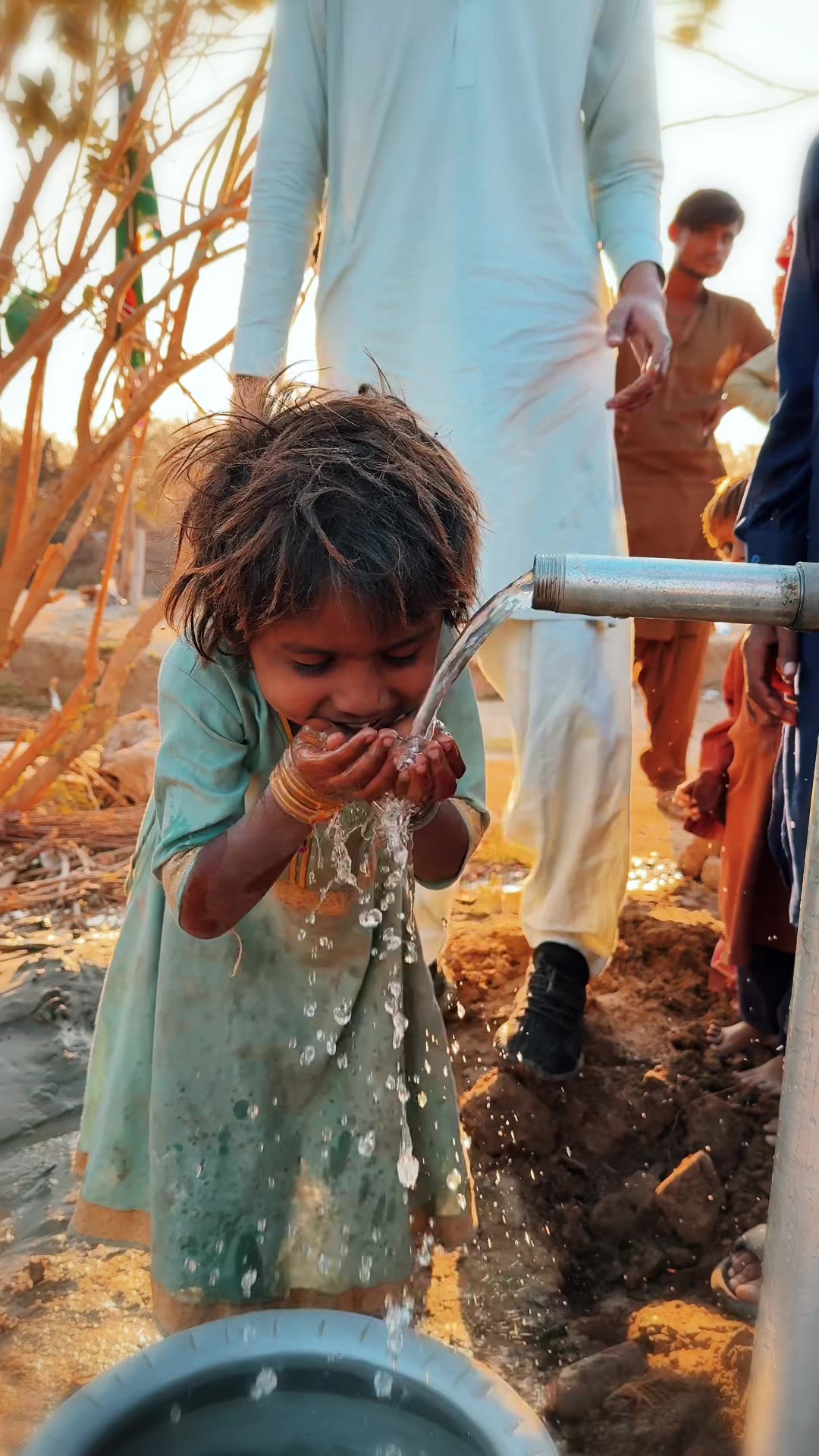 A little girl drinking from a new water pump